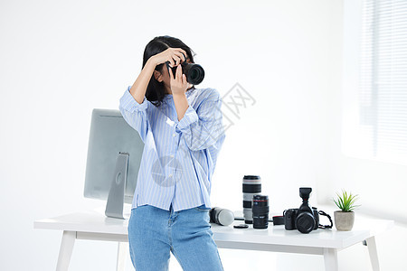 手拿相机拍摄的青年女摄影师图片