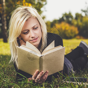 在公园的草地上看书的女孩图片