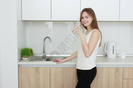 年轻女子在厨房喝水图片