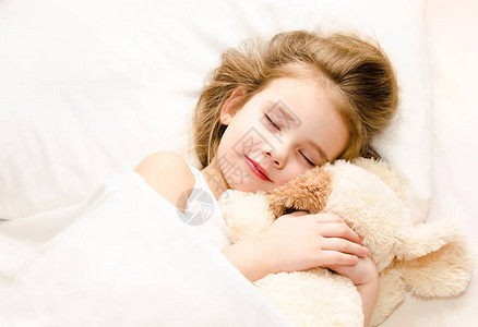 小女孩睡在床上她的玩具图片