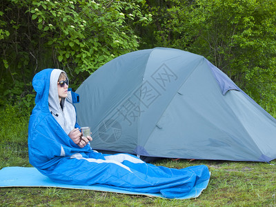 一个男人坐在附近的帐篷睡袋里图片