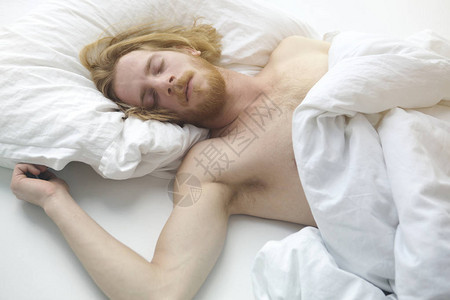 英俊的红发男子躺在床上睡觉图片