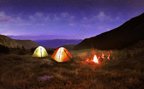 在夜晚的星空下照明黄色野营帐篷图片