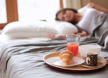 与咖啡和牛角面包吧年轻漂亮的女人床上早餐图片