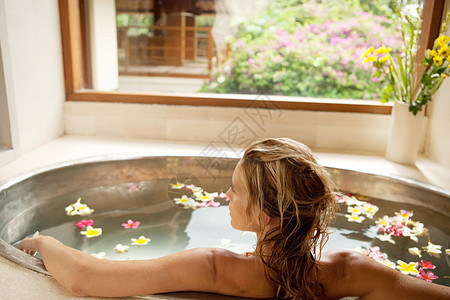 后视图的一个年轻的女人沐浴在健康spa花之浴图片