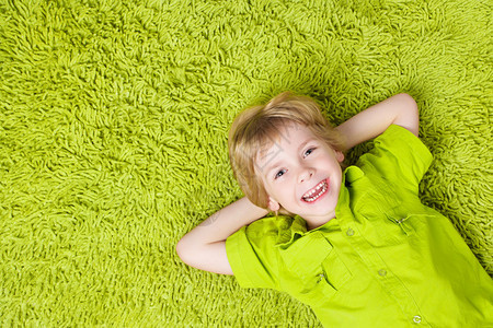 孩子躺在绿地毯背景图片