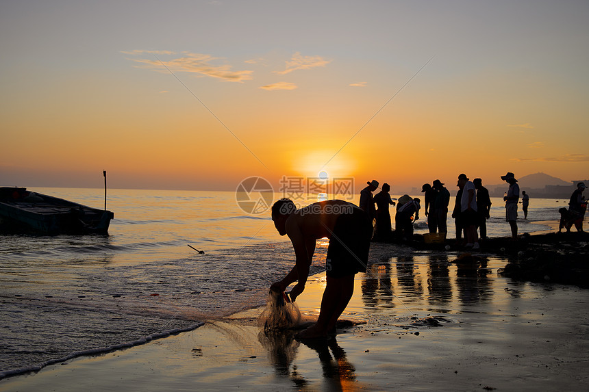 夏天海边夕阳下捕鱼的人图片