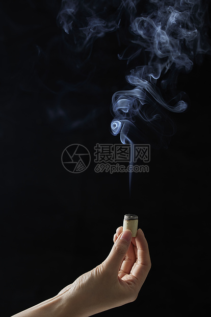 黑色背景手拿艾灸条图片