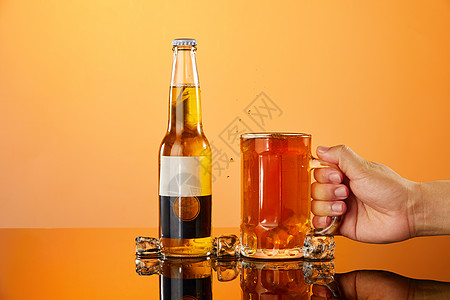拿起酒杯手用手拿起放在桌面上的冰镇啤酒杯背景