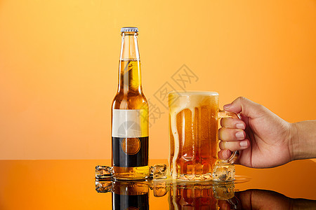 用手拿起放在桌面上的啤酒杯背景图片