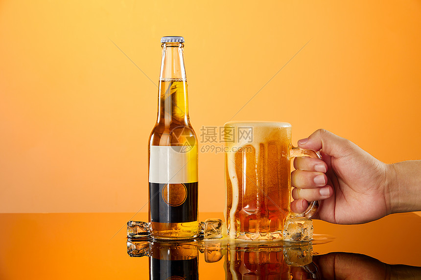 用手拿起放在桌面上的啤酒杯图片