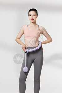 青年健身女性使用便携呼啦圈瘦身器材图片