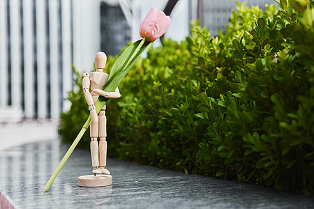 创意木头人模型抱着花朵背景