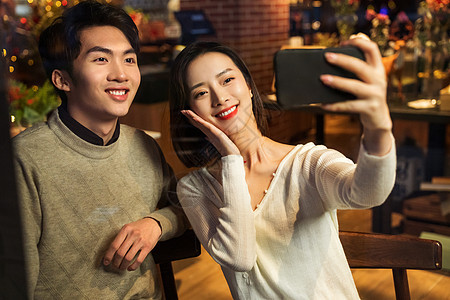 餐厅内的青年伴侣使用手机自拍背景图片