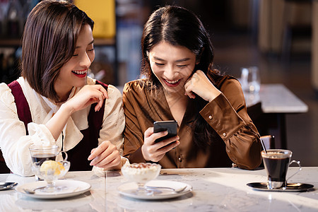 年轻闺蜜在咖啡馆使用手机图片
