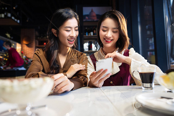 年轻闺蜜在咖啡馆使用手机图片