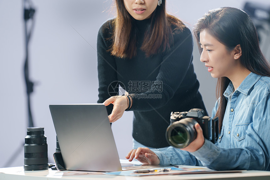 在工作室里讨论工作的青年女摄影师图片
