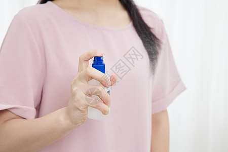 女性手拿消毒液特写背景图片