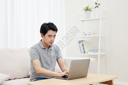 居家男性使用笔记本电脑线上问诊背景图片