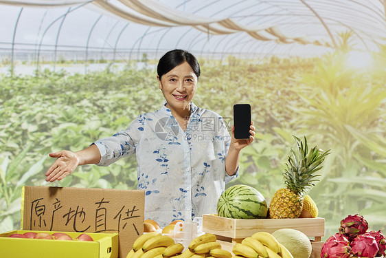 中年女性水果摊拿着手机展示图片