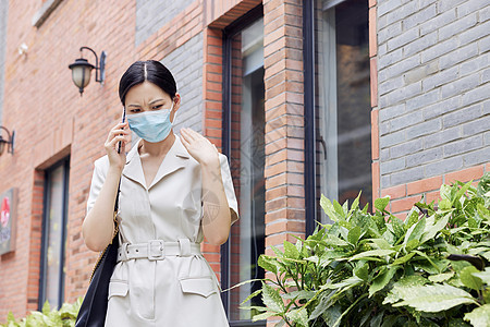 戴口罩的商务女性在室外打电话图片