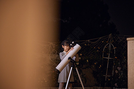 小女孩使用天文望远镜看月亮背景图片