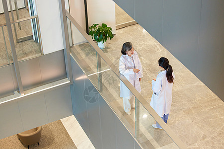医院走廊里的两位女医生交流工作背景图片