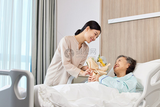 手拿花束的女性探望生病住院的老人图片