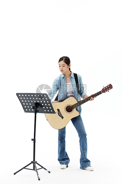 看乐谱弹吉他的青年女性图片
