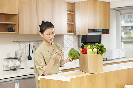 年轻女性居家线上团购蔬菜背景图片