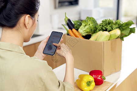 社区配送居家美女使用手机团购蔬菜特写背景