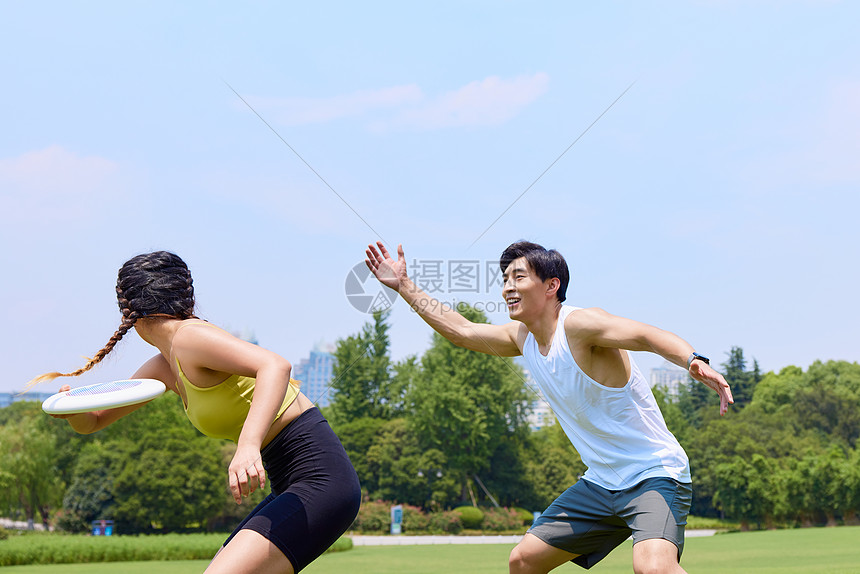 青年男女户外草坪玩飞盘图片