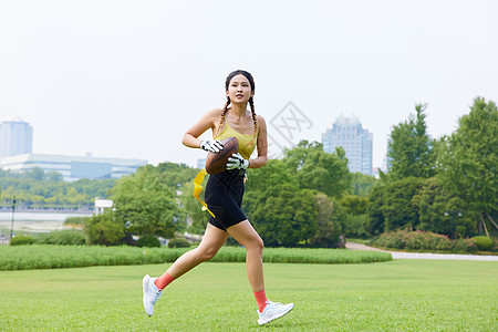 年轻美女抱着橄榄球奔跑图片