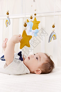 初生宝宝在婴儿床上玩摇铃高清图片