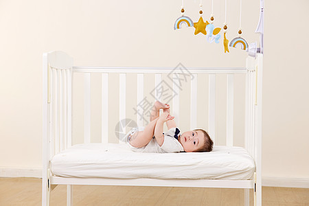 躺在婴儿床上看床铃的婴儿图片