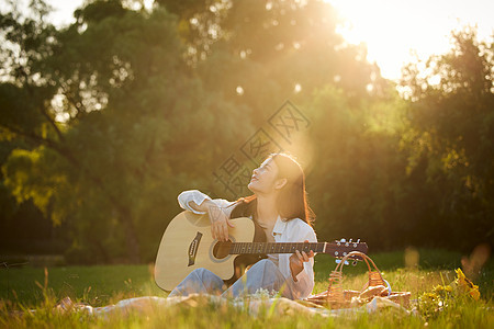 阳光下的元气美女草地上弹吉他图片