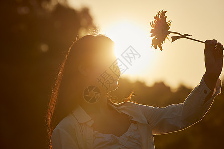 阳光下的女性手拿鲜花图片