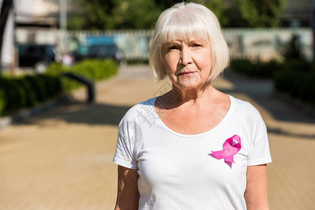 佩戴着粉色丝带宣传关注癌症的老年女性背景图片