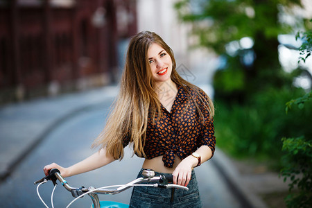 一头长的金发美女推着自行车在街上图片