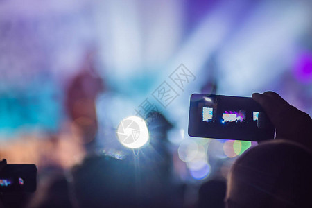 使用先进的移动录音有趣的音乐会和美丽的灯光摇滚音乐会中人群的坦率形象使用智能手机录制视频的特写镜头享受移图片