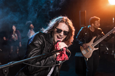 配有麦克风摇滚乐和摇滚乐队的男歌手在舞台上演背景图片