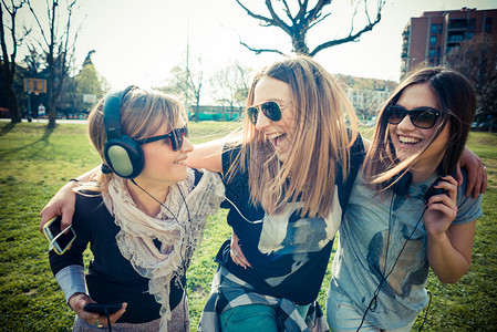 三个戴着墨镜的漂亮女孩在草地上玩乐图片