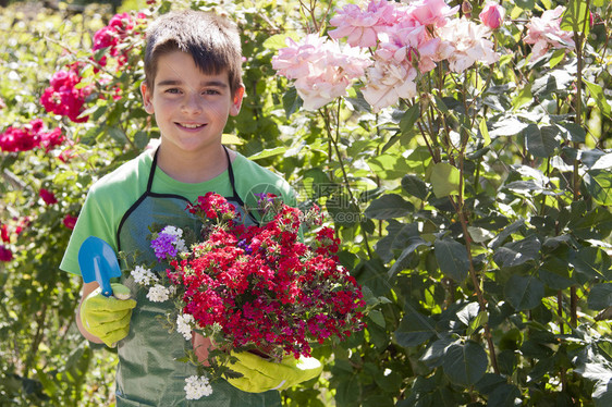 端着漂亮花盆和园艺工具的小男孩图片