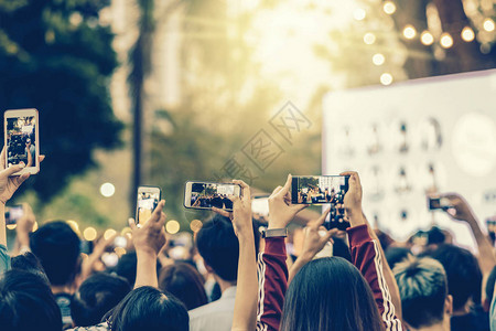 粉丝俱乐部成员在夜间户外音乐娱公共音乐会期间用智能手机拍照音乐图片