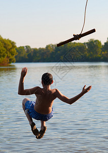 少年男孩在阳光明媚的夏日从摇摆图片