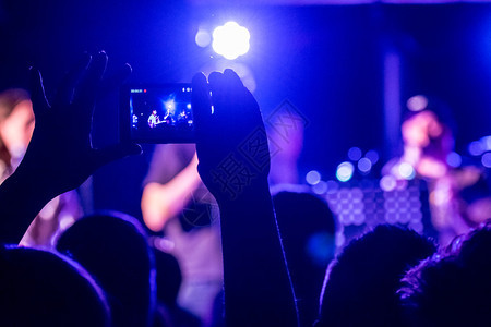 在音乐娱公共音乐会期间拍摄带有触摸智能电话照片的人图片