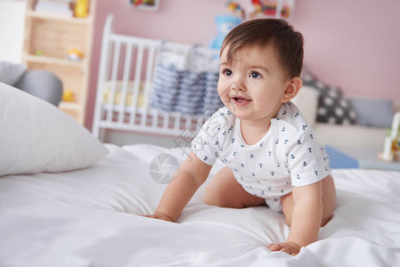 爬行在床上的微笑的男婴图片