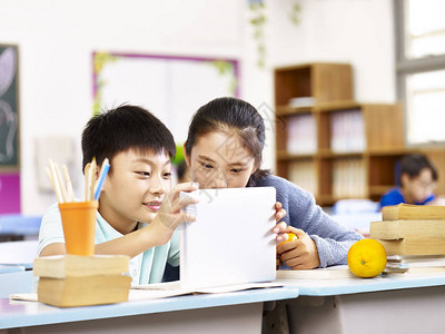 在课堂上一起使用平板电脑的亚洲小学女孩和男孩子图片