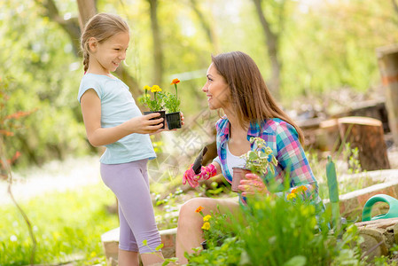 带着女儿在后院种花的年轻女子背景图片