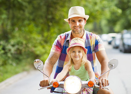 快乐的年轻父亲和小女儿在街上骑着一辆老式摩托车图片